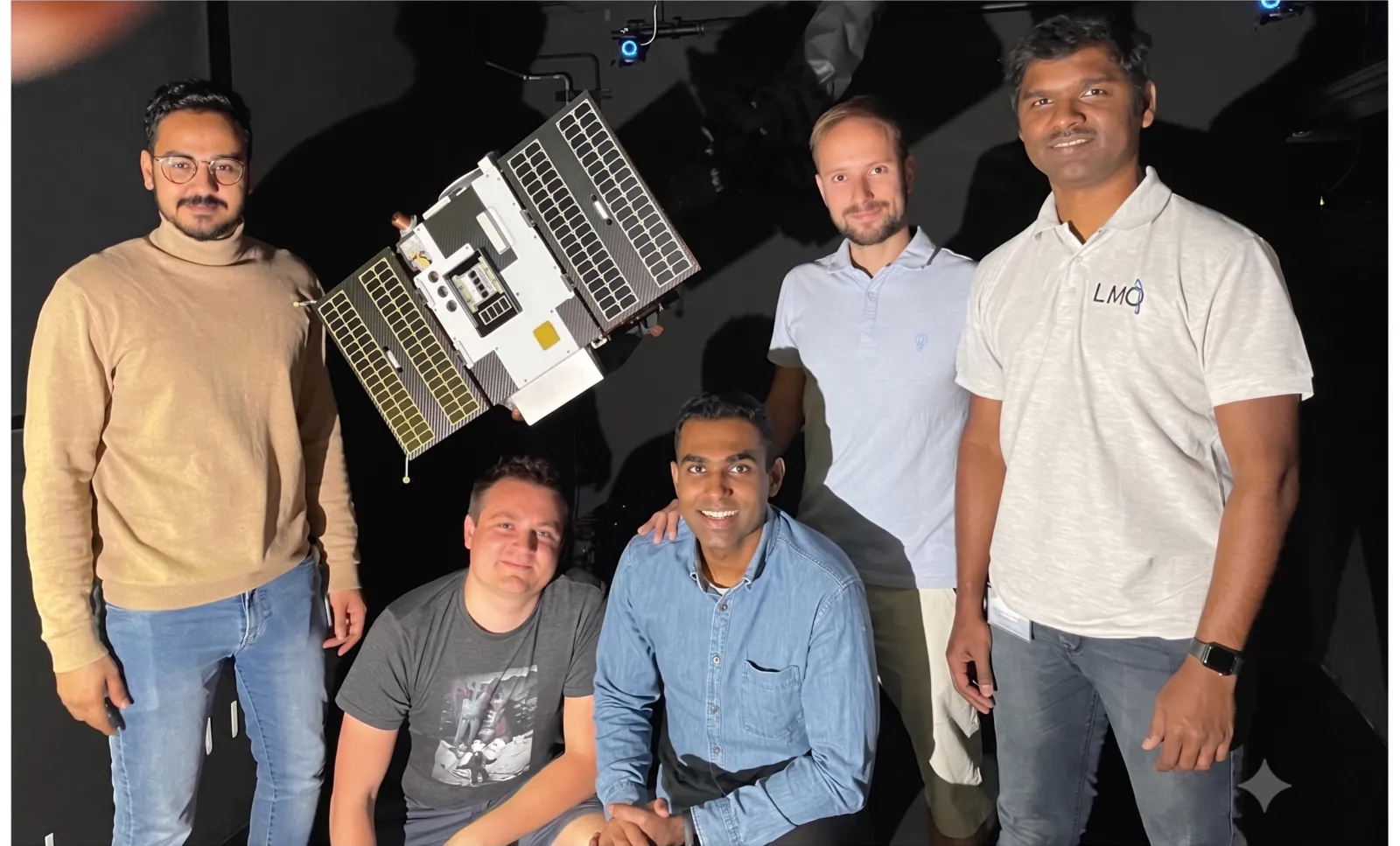 Leo Pauly with four colleagues in a clean studio, posing with a micro-satellite flight model.